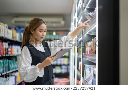 supermarket clerk using apps on a digital tablet, innovative technology, and work concept, and a young female supervisor with a tablet pc in the mall. Royalty-Free Stock Photo #2239239421