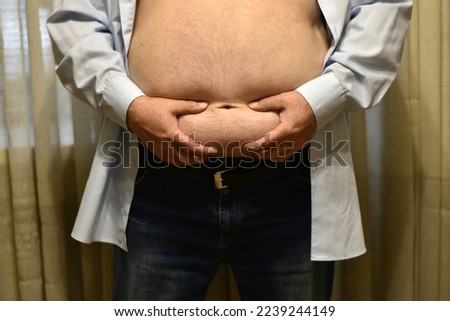 The picture shows a shirtless man with a big fat belly, who squeezes his hands.