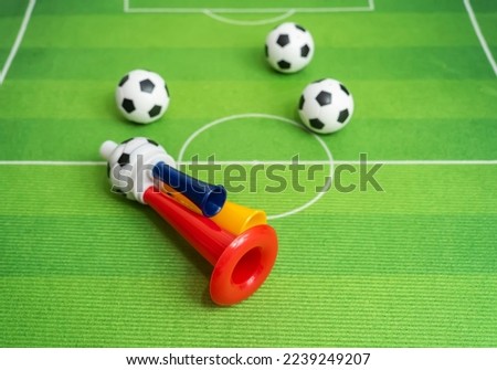Football soccer triple fan trumpet with toy football on green grass