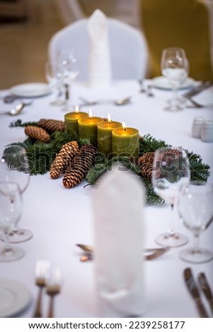 Festive decorated holiday Christmas table with traditional winter seasonal table ornaments made of pine tree branches, cones, and various wax candles