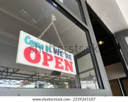 Text on vintage white sign with colorful font "Come in we're open" in a coffee house