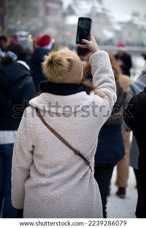 Portrait on view of young woman taking a photo with her smartphone in the street