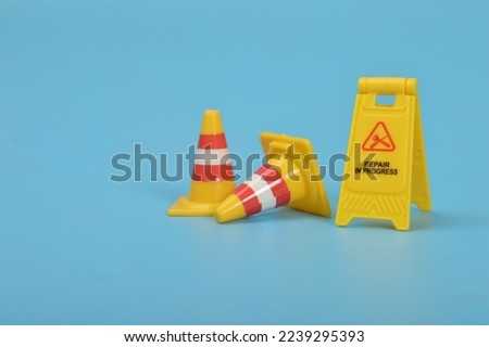 Repair In Progress sign and safety plastic cones isolated on a blue background.