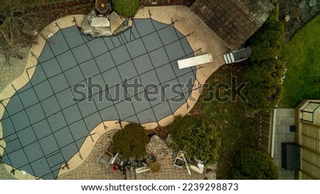 Aerial drone shot of a closed and covered backyard swimming pool with a diving board in the fall Royalty-Free Stock Photo #2239298873