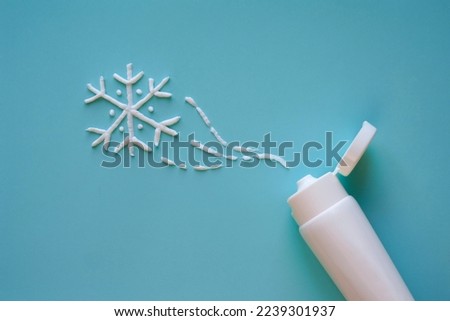 Tube and snowflake from cream on a blue background. Winter skin care