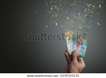 Inflation of swiss francs banknotes vanishing into nothing  Man hand holding 10 and 50 swiss francs dispersing into thin air or nothing  Royalty-Free Stock Photo #2239310131