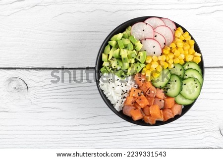 Poke bowl with salmon, rice, cucumber, corn, radish, avocado on a white background. Top view, copy space. Hawaiian traditional food. 