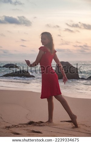 Silhouette rear view slim woman in red dress dancing on ocean beach at sunset background. Lady on sea beach in summer vacation, sunny, having fun, romantic, relax, happy. Copy space