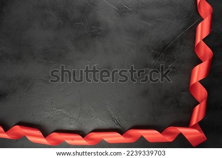 Red ribbon on black background. Flat lay. Copy space