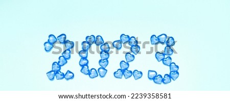 New Year 2023 inscription from glass hearts on a blue background. Pantone color 2023. Idea and creativity. Valentine's Day. Christmas with loved ones. Horizontally, banner. High quality photo