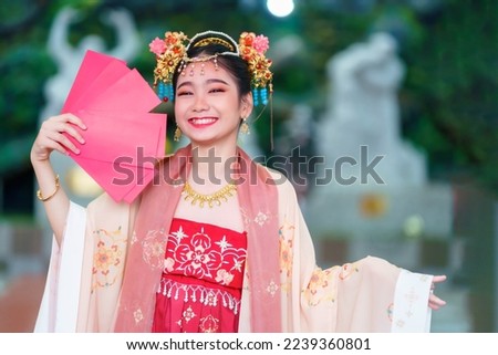 Asian Happy little girl wearing Chinese costumes holding red envelopes decoration for Chinese new year festival celebrate culture of china at Chinese shrine Public places in Thailand