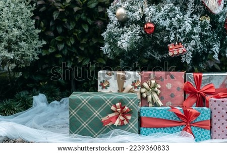 Merry x-mas,Close up of multiple gift boxes,Colorful balls and Christmas greeting picture parcel,Santa doll decoration on Green Christmas tree background Decoration During Christmas and New Year.