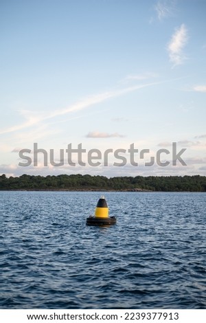Buoy on the sea with a forest in the background during the sunse