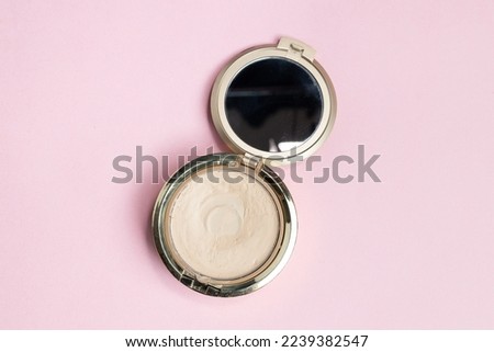 Portable makeup mirror for women on pink pastel background. Top view