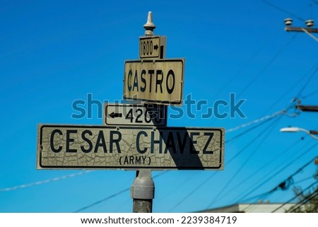 Road sign in the historic districts of san francisco california says cesar chavez and castro with white and black paint on metal pole. Late in afternoon sun and shade with blue and white gradient sky.