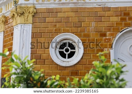 Antique building with round window with cross frame