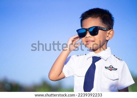 A boy wearing a white flight suit of a major airline on a blue background.