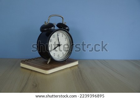 close up of alarm clock and a book on the table
