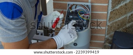 Electrician technician carrying out the repair and programming of a technical data sheet of the motor of an automatic driveway gate. Horizontal banner 
