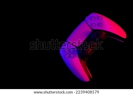 Modern white gamepad illuminated red and blue on a black background, copy space, game controller for video games.