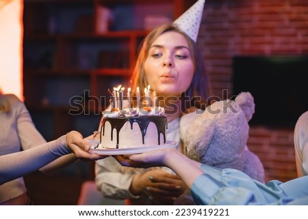 Girl in party cone standing near a plate with a cake and celebrating birthday