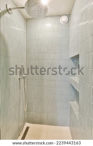 a walk in shower with white tiles on the walls and floor, along with an overhead shower head mounted to the wall