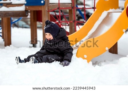 A little boy walks on the playground. The child is having fun riding down the hill. Childhood and child development.