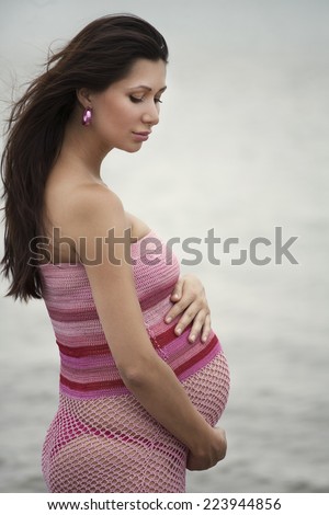 portrait of a pregnant girl sitting on a lake