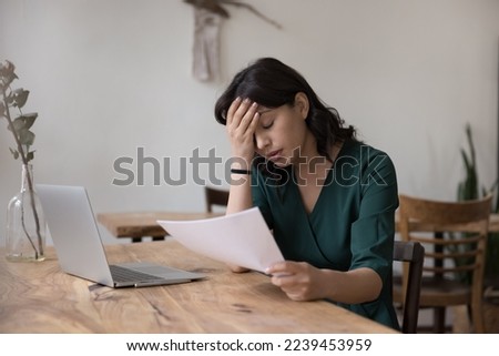 Upset exhausted freelance employee woman getting job report with mistake, holding paper document at work table with laptop, touching head with closed eyes, doing boring paperwork Royalty-Free Stock Photo #2239453959