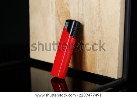 Stylish presentation of red plastic cigarette lighter near wooden surface