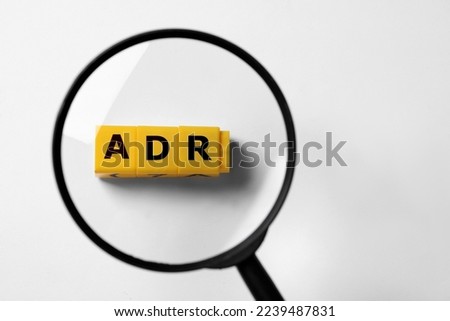 Alternative dispute resolution. Top view through magnifying glass on yellow cubes with letters ADR, white background Royalty-Free Stock Photo #2239487831