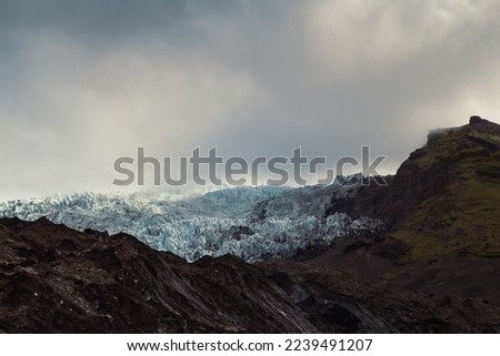 Rocky mountain ridge with ice landscape photo. Beautiful nature scenery photography with gloomy sky on background. Idyllic scene. High quality picture for wallpaper, travel blog, magazine, article