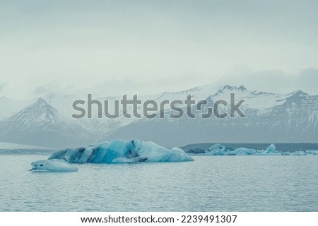 Blue icebergs floating near coast landscape photo. Beautiful nature scenery photography with mountain on background. Idyllic scene. High quality picture for wallpaper, travel blog, magazine, article