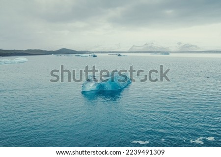 Turquoise iceberg in cold sea landscape photo. Beautiful nature scenery photography with cloudy sky on background. Idyllic scene. High quality picture for wallpaper, travel blog, magazine, article