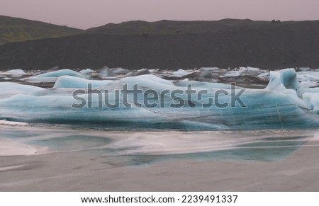 Frozen waves on northern lake landscape photo. Beautiful nature scenery photography with mountain on background. Idyllic scene. High quality picture for wallpaper, travel blog, magazine, article