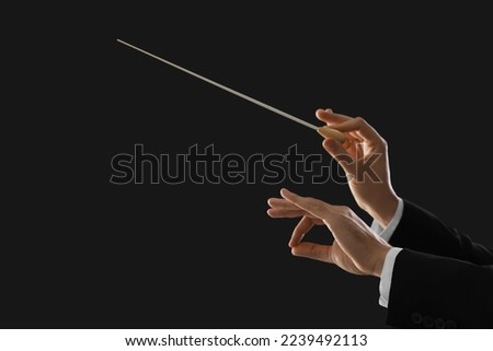 Professional conductor with baton on black background, closeup. Space for text Royalty-Free Stock Photo #2239492113