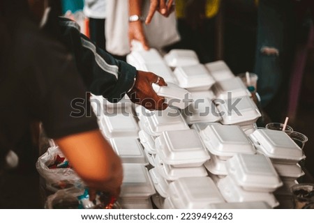 Concept of giving free food to the poor in the community : Volunteers handing out food to hungry people Royalty-Free Stock Photo #2239494263