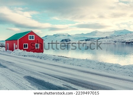 Red cabin on snowy sea coast landscape photo. Beautiful nature scenery photography with mountains on background. Idyllic scene. High quality picture for wallpaper, travel blog, magazine, article