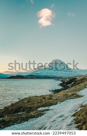 Snowy mountain near sea bay landscape photo. Beautiful nature scenery photography with cloudy sky on background. Idyllic scene. High quality picture for wallpaper, travel blog, magazine, article