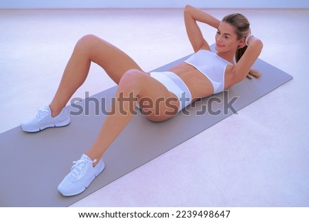Young fit woman training, doing abs workut, crunch exercise in neon colored gym class 