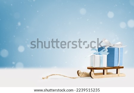 wooden sledge with gifts on a light blue background. winter background with copy space