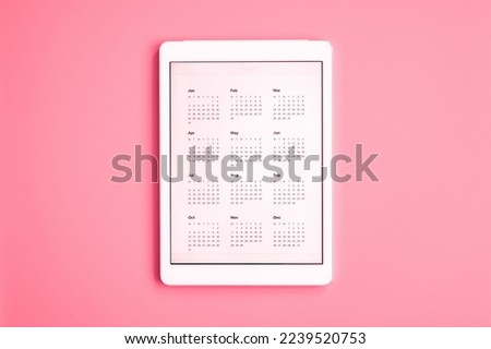 tablet computer with app of calendar for unspecified unknown date year without date. business or to do list goals. top view, flat lay. toned in viva magenta, trend color of the year 2023