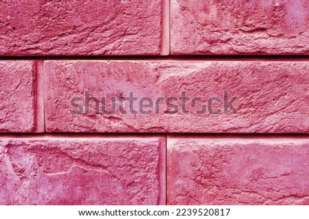 pattern of decorative pink slate stone wall surface as a background. toned in viva magenta, trend color of the year 2023