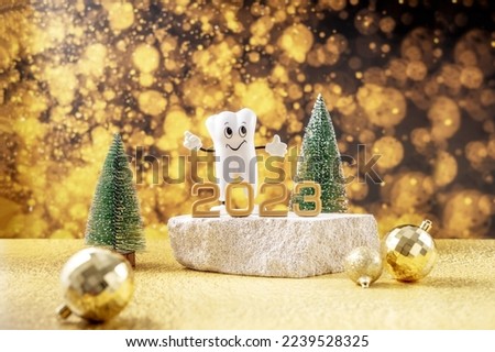  cartoon model of a tooth, the numbers 2023 and a tube of toothpaste on a podium made of stone and Christmas trees on a background of golden bokeh