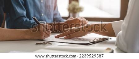 financial investor advisory.  Close up hand pointing at contract and document while sitting together with young couple at the desk in office