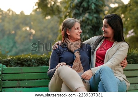 Two indian woman sitting at park in winter wear Royalty-Free Stock Photo #2239537031