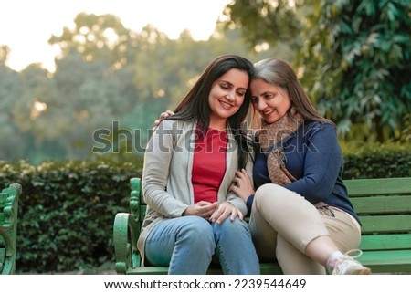 Two indian woman sitting at park in winter wear Royalty-Free Stock Photo #2239544649