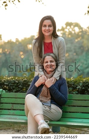 Two indian woman sitting at park in winter wear Royalty-Free Stock Photo #2239544669