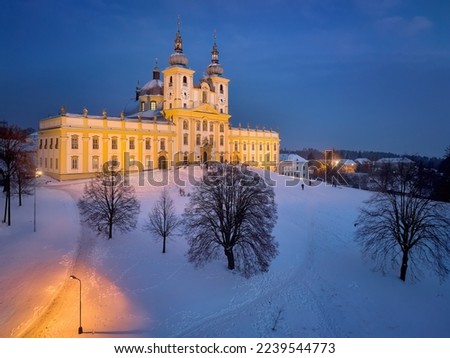 Aerial, late evening view of illuminated Minor Basilica of the Visitation of the Virgin Mary, pilgrimage church covered with snow. Blue hour, pastel colors, Christmas time, Moravia, Czech republic.