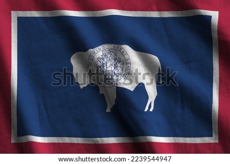 Wyoming US state flag with big folds waving close up under the studio light indoors. The official symbols and colors in fabric banner